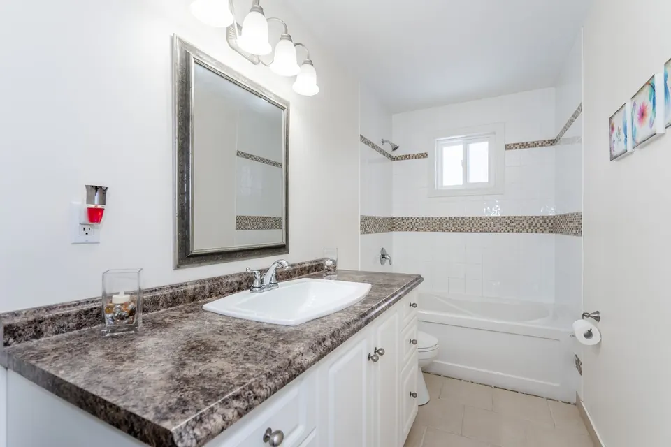 A bright bathroom with fresh white walls and a granite vanity