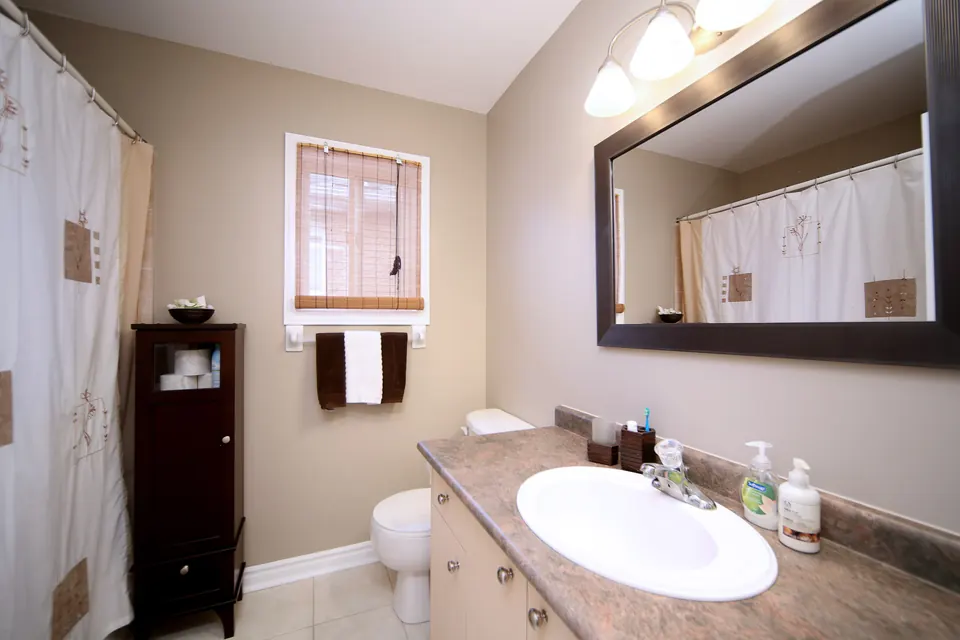A bathroom with warm taupe walls and a framed mirror