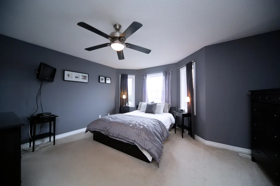 A spacious bedroom painted in a cool grey with white trim