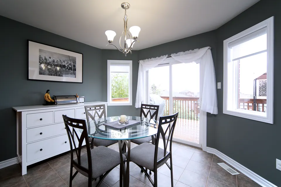 A dining nook with charcoal walls, white trim and a chandelier