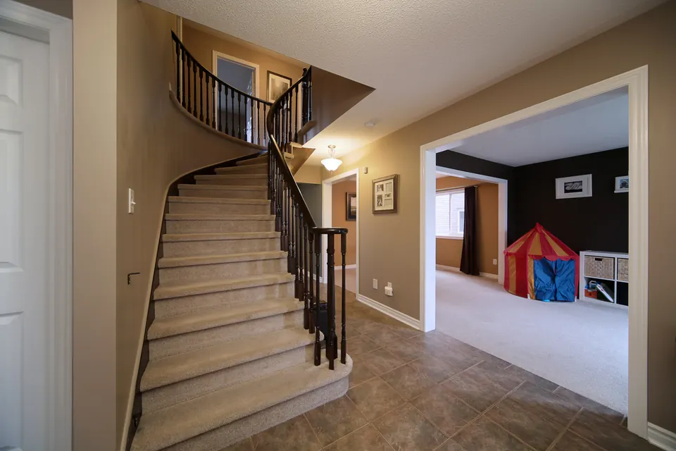 An entryway with a curved staircase and warm beige walls