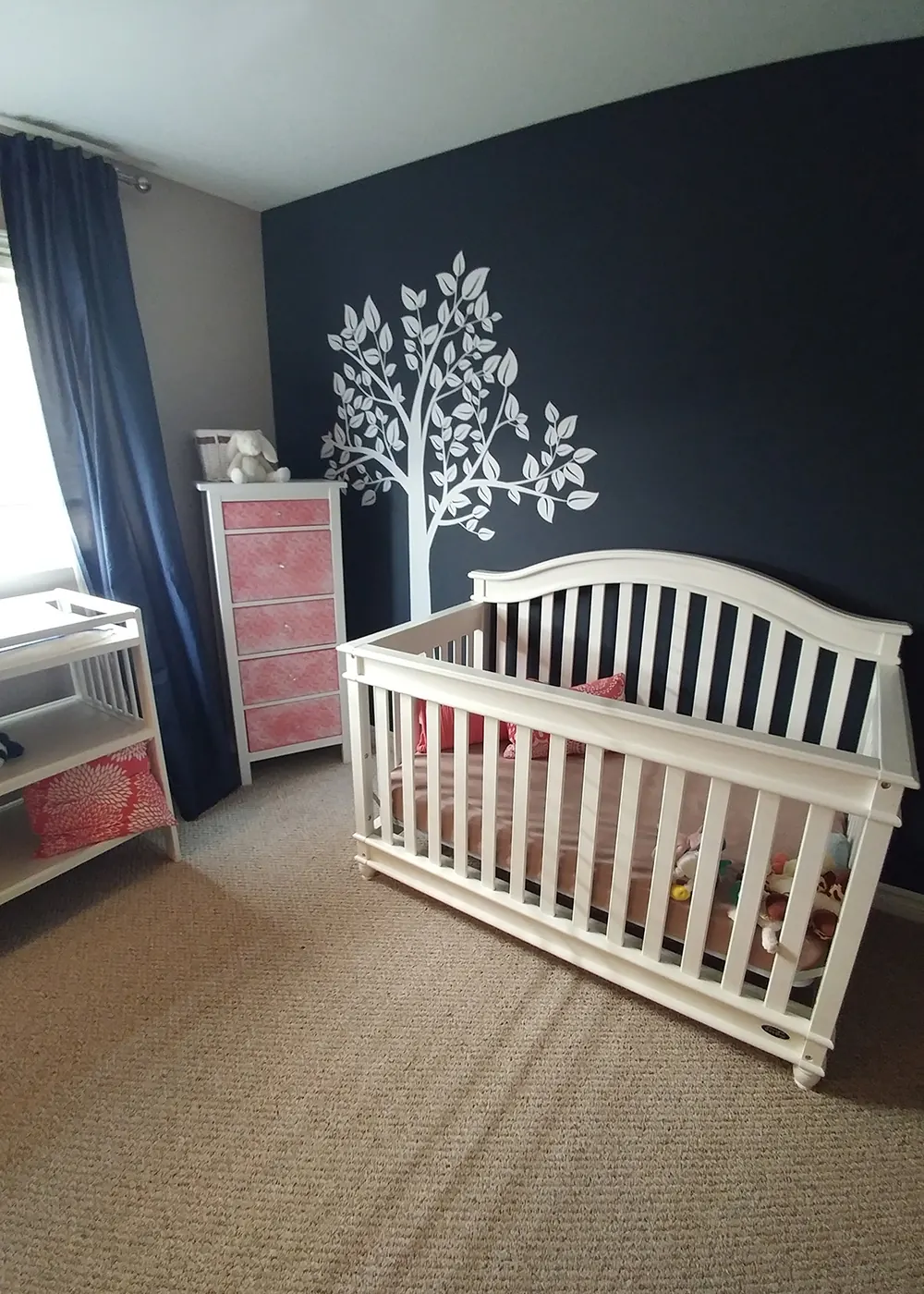 A nursery with a deep navy feature wall and white crib